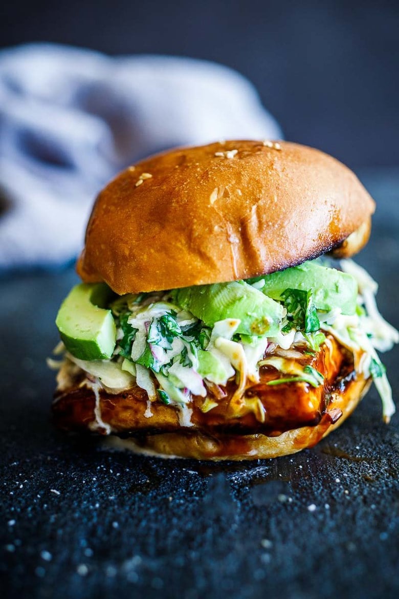 Crispy BBQ tofu sandwich with brioche buns, avocado slices, and slaw. 