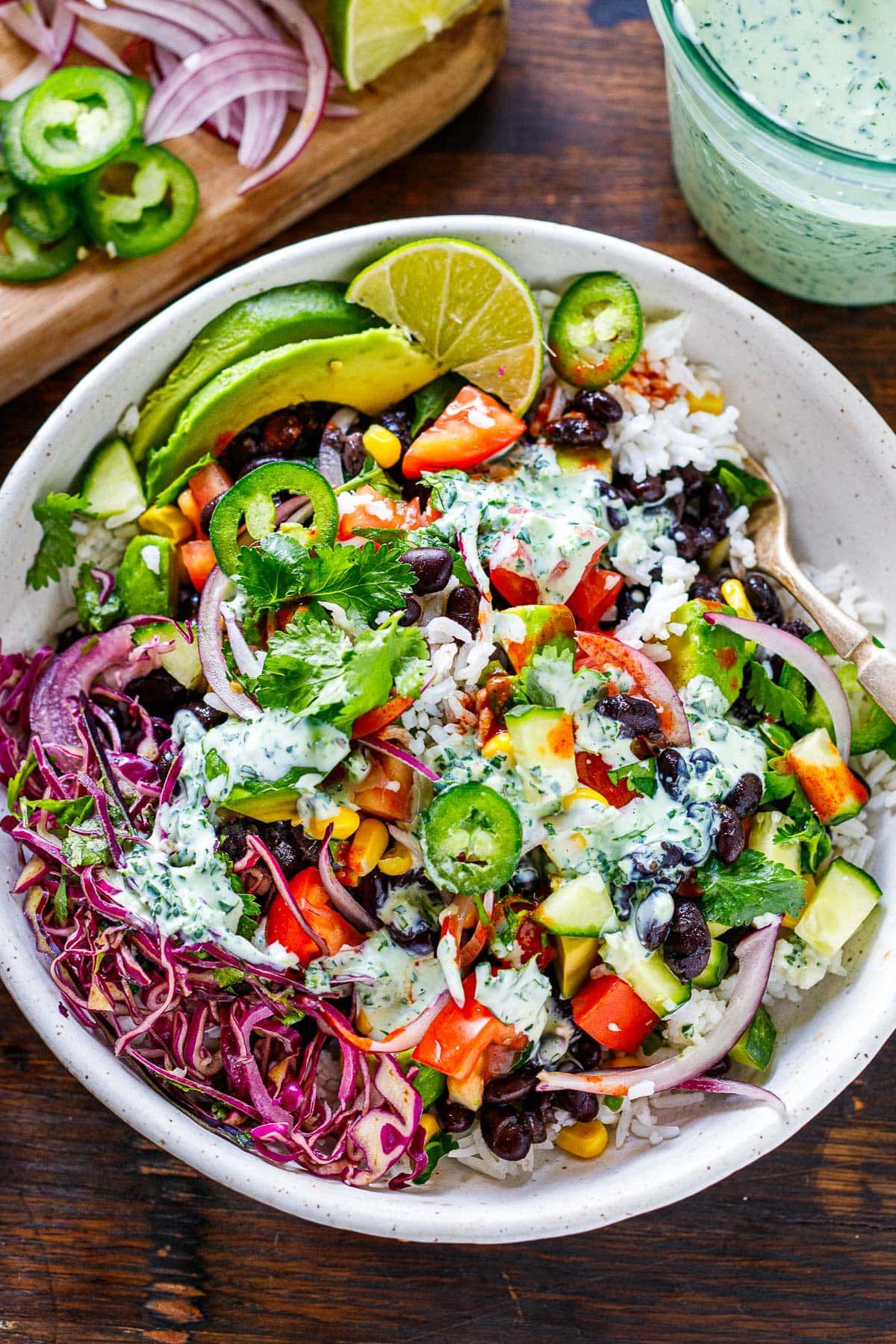 Assembled burrito bowl topped with cilantro lime crema. 