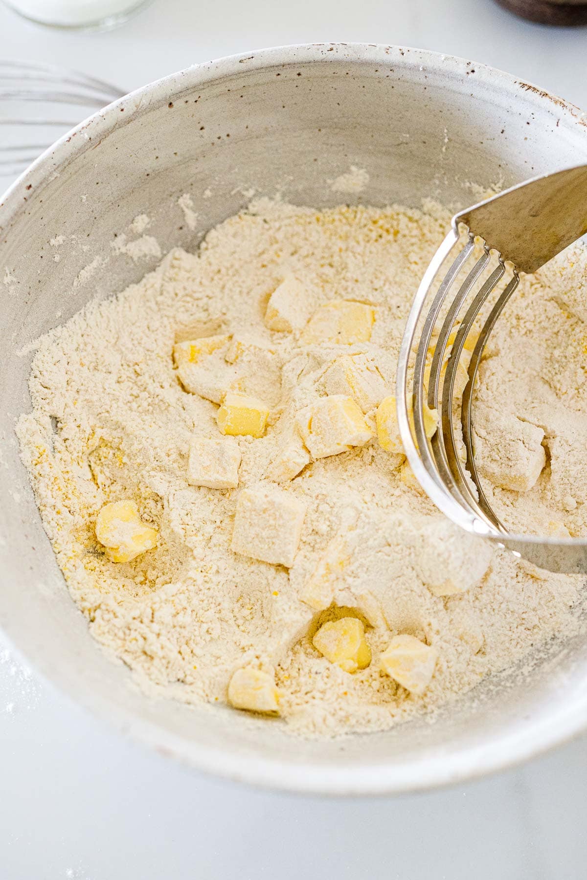 large mixing bowl with galette dry ingredients with cubed butter and pastry cutter. 