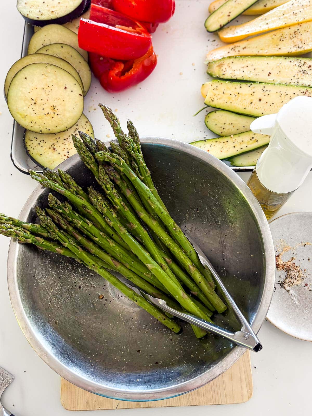 seasoning asparagus in a bowl with olive oil and seasonings for the grill. 