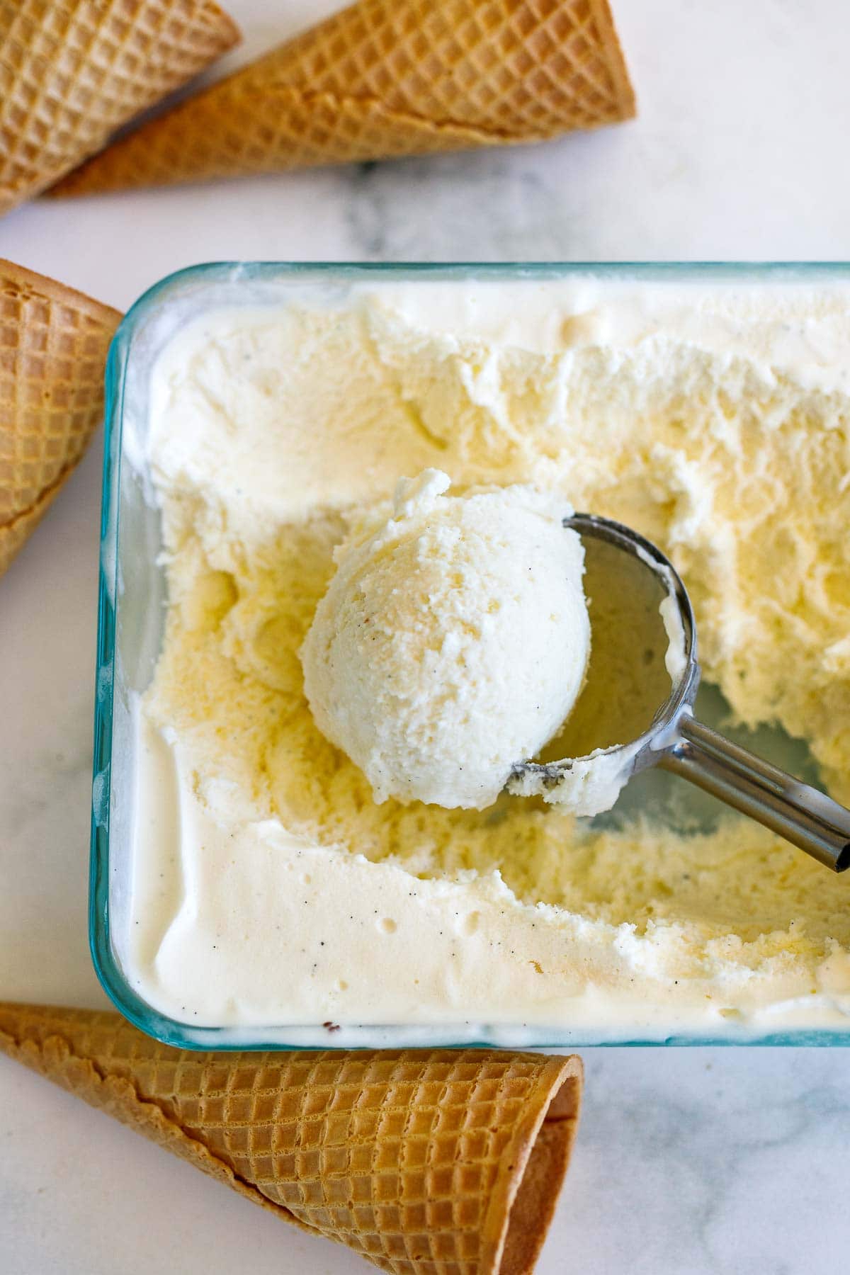 ice cream scoop scooping homemade ice cream surrounded by ice cream cones. 