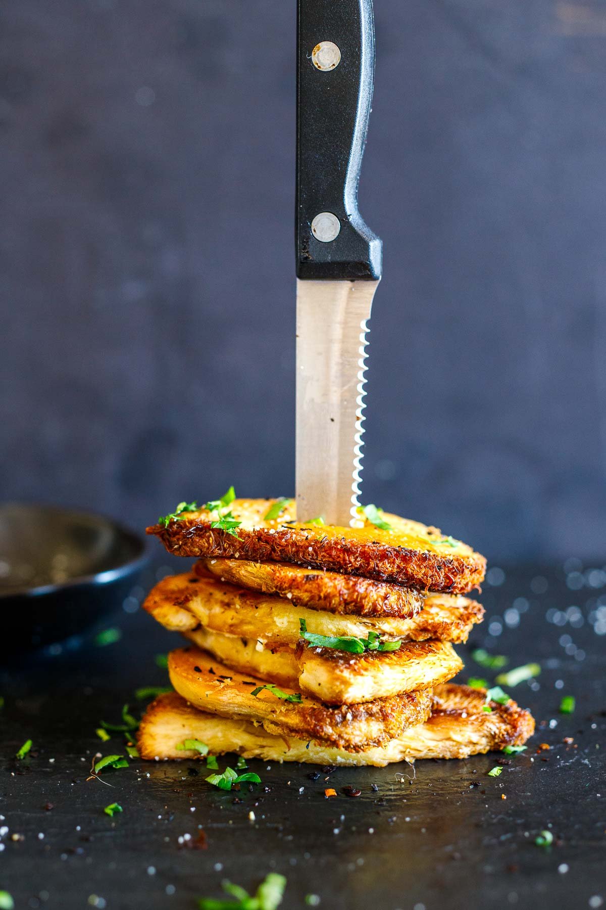 stacked slices of seared lion's mane on a counter with a knife sticking out!