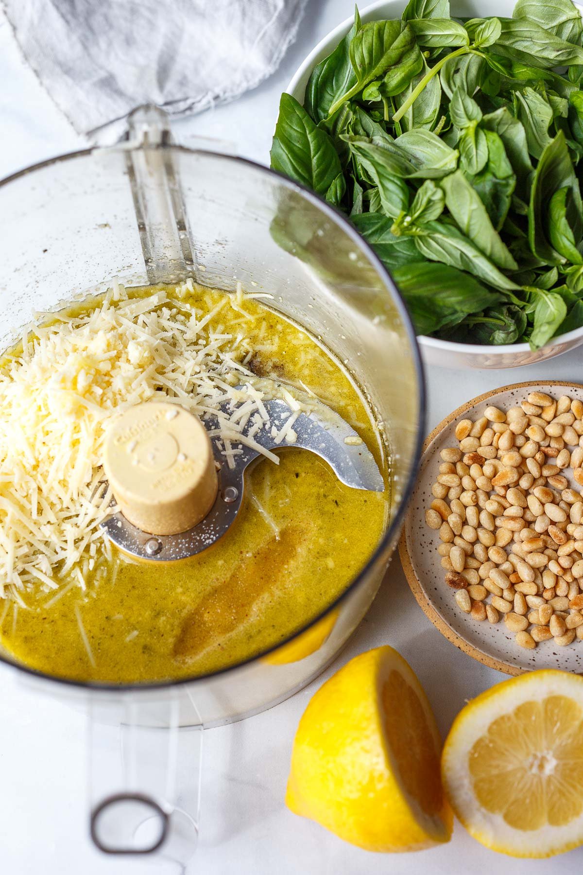 Food processor with parmesan, olive oil, basil, pinenuts, lemon.