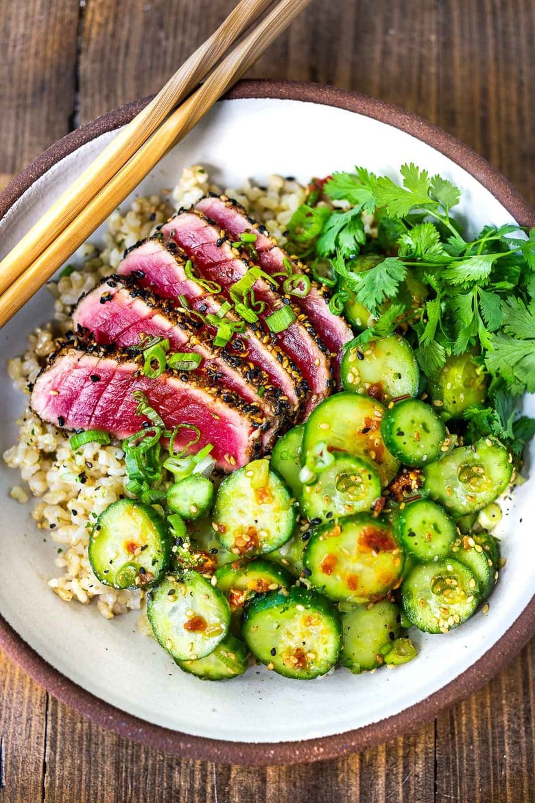 Seared Tuna with Sesame Crust with Asian cucumber salad, over sushi rice in a bowl with chop sticks. 