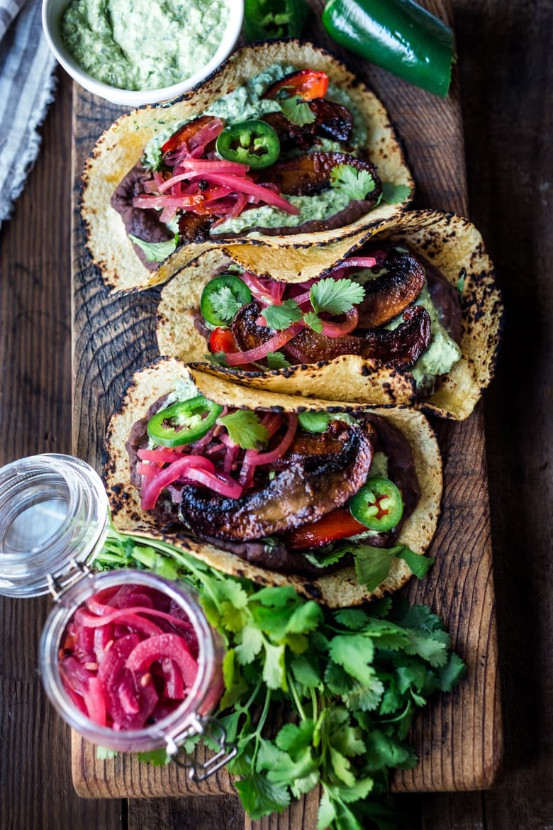 chipotle portobello tacos on wood plank, topped with refried black beans, roasted portobellos, pickled onions, fresh jalapeno, and cilantro. 