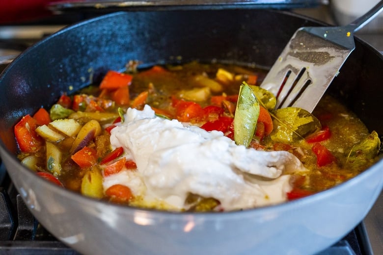 pan of veggies and broth with coconut milk added. 