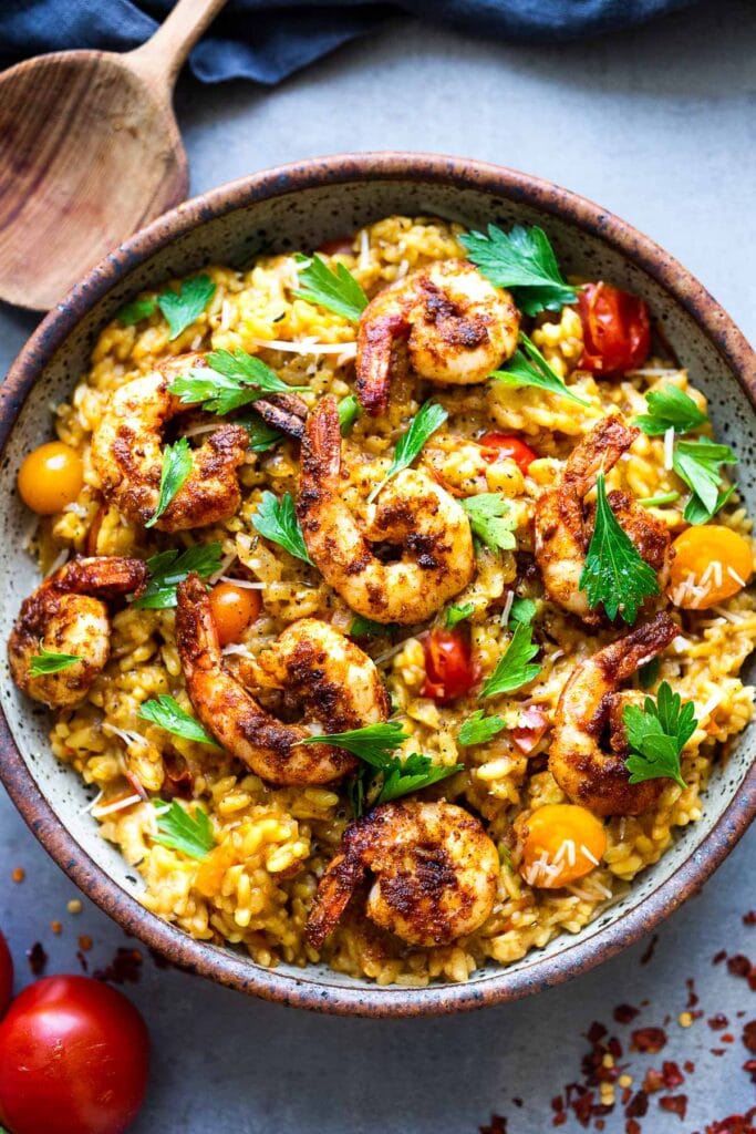 Summer Tomato Risotto in bowl topped with smoky shrimp, blistered cherry tomatoes, and fresh parsley. 